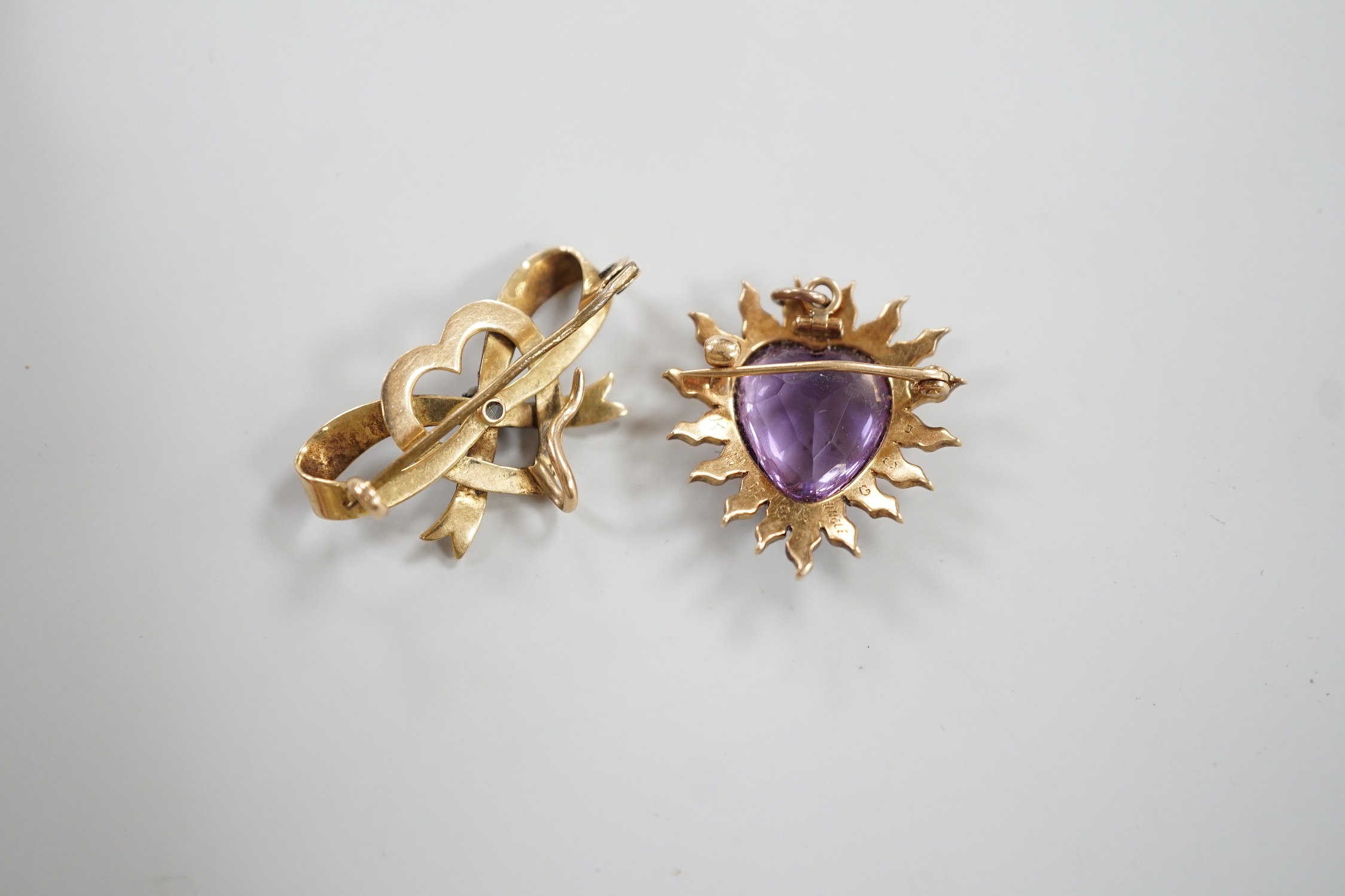 An early 20th century yellow metal amethyst and seed peart set heart shaped pendant brooch, 25mm, gross 5.3 grams and a yellow metal and enamel set ribbon bow and heart brooch (enamel a.f.).